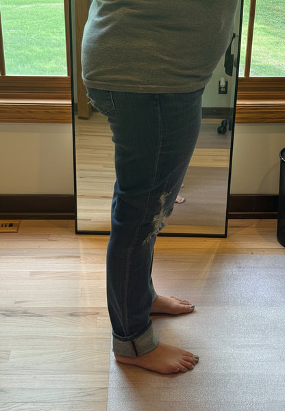 Plus size model wearing Judy Blue mid rise boyfriend jeans in dark wash size 15, side view showing relaxed fit and faux selvedge cuff